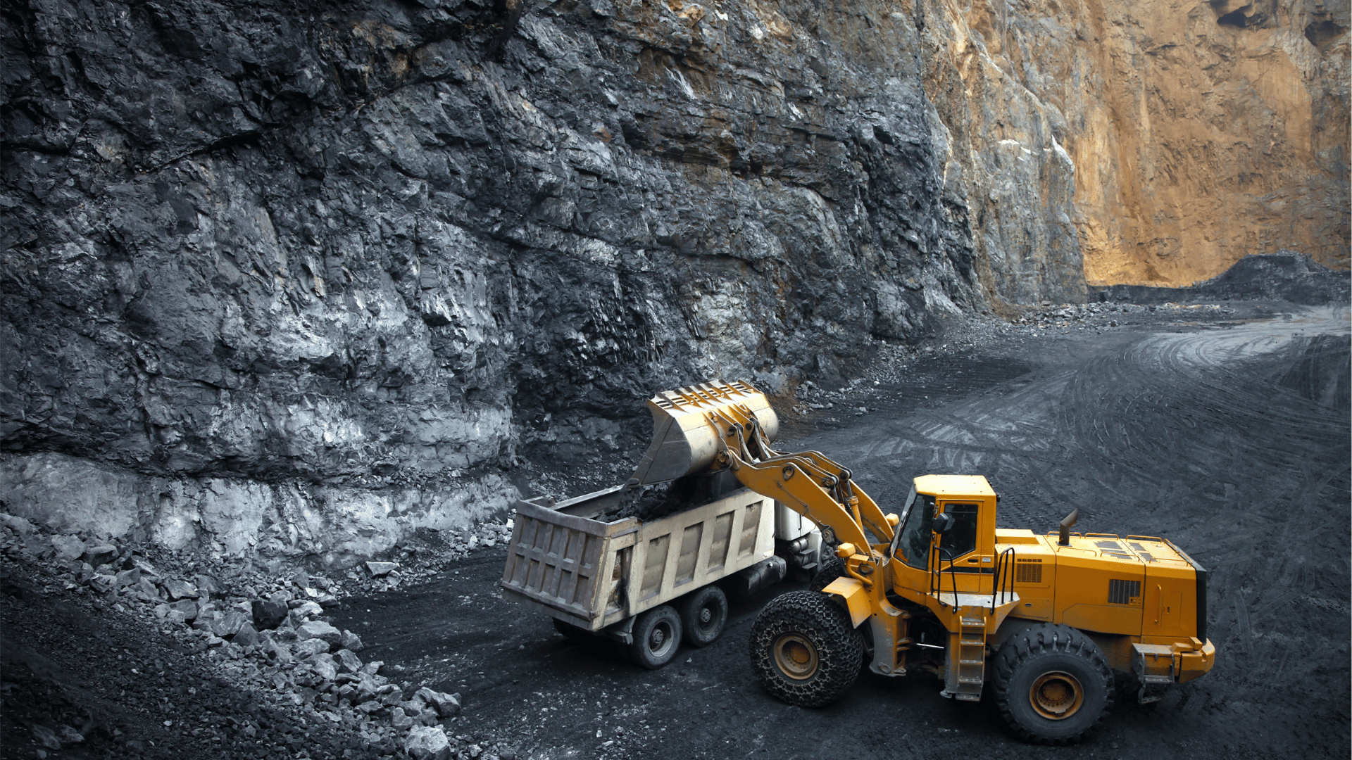 Wheel loader transferring ore into a haul truck at a mining operation.